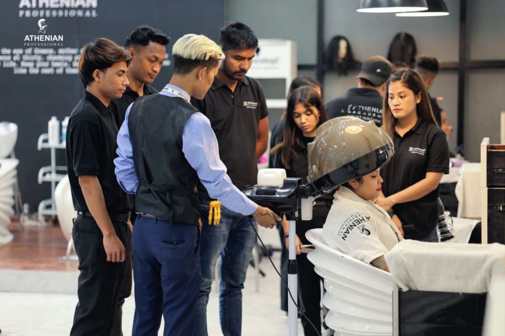 Instructor demonstrating salon hair treatment with students at Athenian Professional